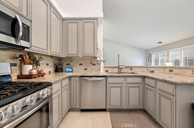 27242 Cabrillo Dr, Menifee, CA 92586 - kitchen featuring appliances with stainless steel finishes, tasteful backsplash, light stone counters, and a peninsula
