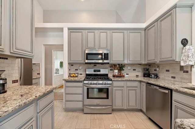 27242 Cabrillo Dr, Menifee, CA 92586 - kitchen with appliances with stainless steel finishes, tasteful backsplash, gray cabinetry, light stone counters, and light tile patterned floors