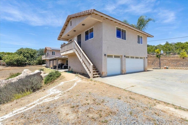 28880 Mac Tan Rd, Valley Center, CA 92082 - view of home's exterior featuring an attached garage, stairway, concrete driveway, stucco siding, and a wooden deck