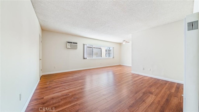 6045 Hazelhurst Pl, North Hollywood, CA 91606 - empty room with a textured ceiling, wood finished floors, a wall mounted AC, and ceiling fan