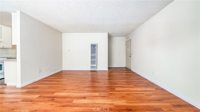 6045 Hazelhurst Pl, North Hollywood, CA 91606 - unfurnished living room with a heating unit, light wood-style flooring, and a textured ceiling