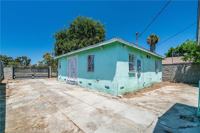 11860 Athens Way, Los Angeles, CA 90061 - view of side of home featuring crawl space, a gate, stucco siding, and concrete driveway