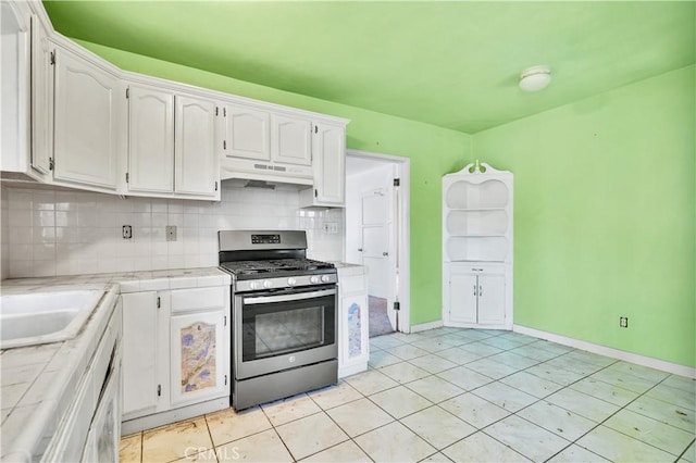 11860 Athens Way, Los Angeles, CA 90061 - kitchen with gas range, tile countertops, under cabinet range hood, white cabinetry, and backsplash