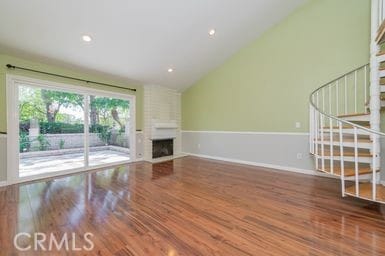 14 Featherwood, Irvine, CA 92612 - unfurnished living room with stairway, wood finished floors, lofted ceiling, and a fireplace
