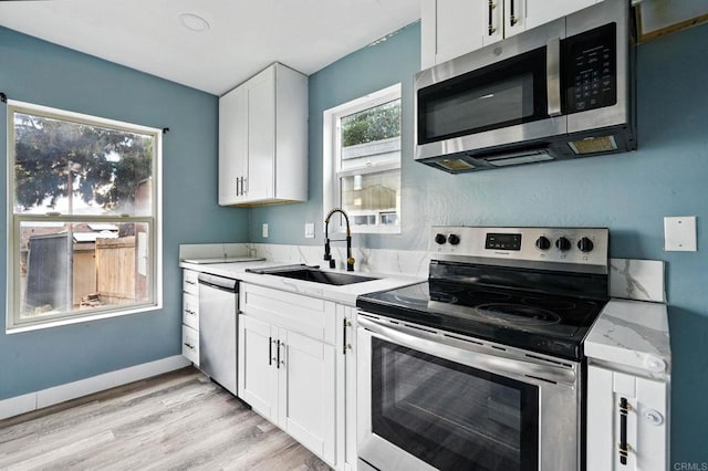 12049 Coping Pl, Lakeside, CA 92040 - kitchen with appliances with stainless steel finishes, white cabinetry, light wood-style flooring, and light stone countertops