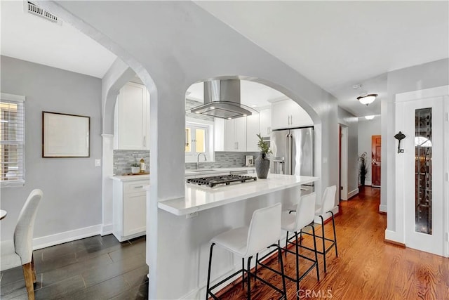 218 Covina Ave, Long Beach, CA 90803 - kitchen featuring stainless steel appliances, island exhaust hood, white cabinetry, backsplash, and light countertops