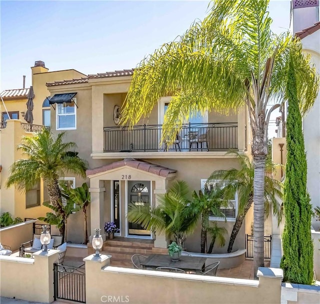 218 Covina Ave, Long Beach, CA 90803 - view of front of house featuring a balcony, a fenced front yard, stucco siding, a chimney, and a gate