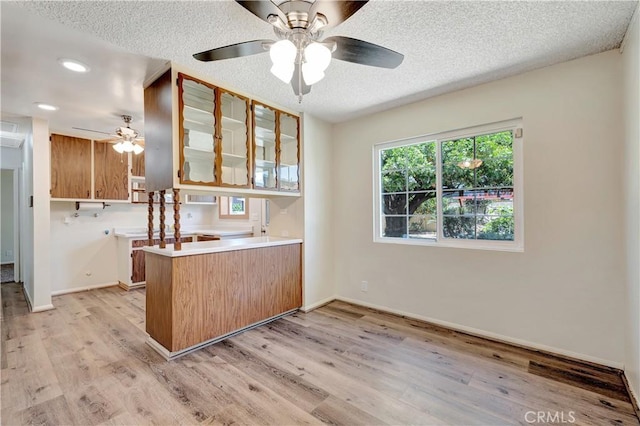 13925 Belgate St, Baldwin Park, CA 91706 - kitchen featuring a ceiling fan, light wood finished floors, a peninsula, glass insert cabinets, and a textured ceiling