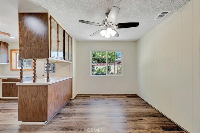 13925 Belgate St, Baldwin Park, CA 91706 - kitchen with ceiling fan, glass insert cabinets, a textured ceiling, wood finished floors, and a peninsula