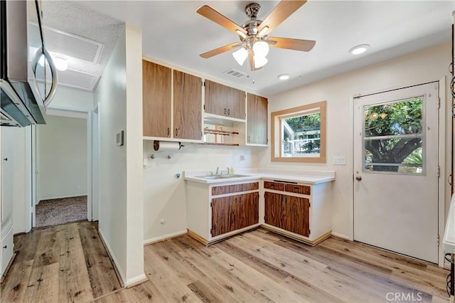 13925 Belgate St, Baldwin Park, CA 91706 - kitchen with stainless steel microwave, light wood finished floors, light countertops, brown cabinetry, and open shelves