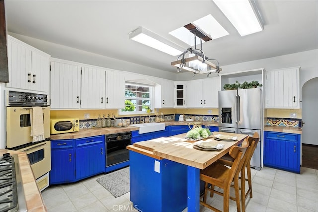 1215 S Patton Ave, San Pedro, CA 90731 - kitchen featuring stainless steel appliances, butcher block countertops, blue cabinetry, and light tile patterned floors