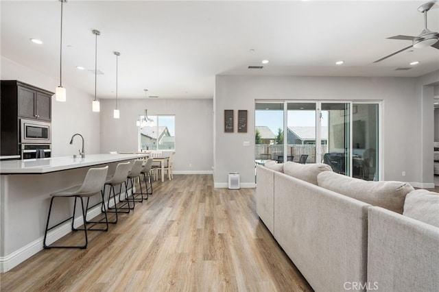 2070 Solig Ave, Kingsburg, CA 93631 - living room with a ceiling fan, light wood-type flooring, healthy amount of natural light, recessed lighting, and a chandelier