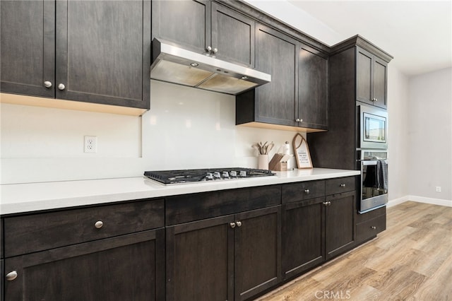 2070 Solig Ave, Kingsburg, CA 93631 - kitchen with appliances with stainless steel finishes, under cabinet range hood, light wood-style floors, and light countertops