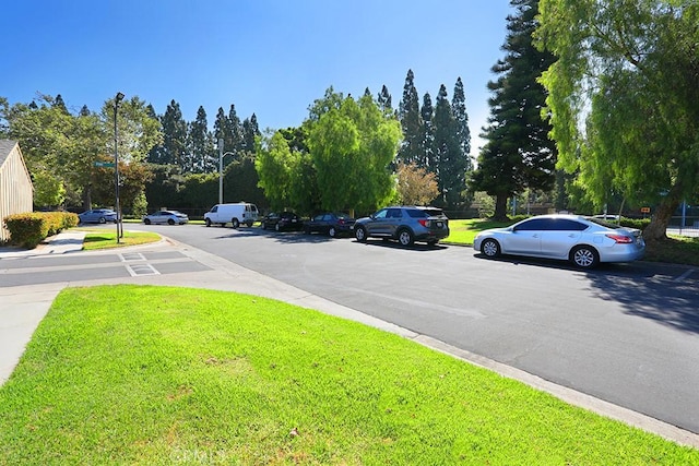 1201 W Cerritos Ave Unit 68, Anaheim, CA 92802 - view of asphalt road with street lights, curbs, and view of wooded area