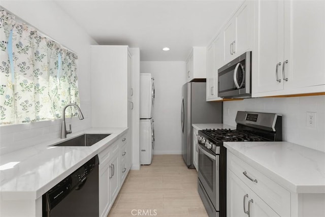 17695 Brittany Ln Unit 74, Huntington Beach, CA 92647 - kitchen with stainless steel appliances, stacked washer and clothes dryer, tasteful backsplash, white cabinets, and recessed lighting