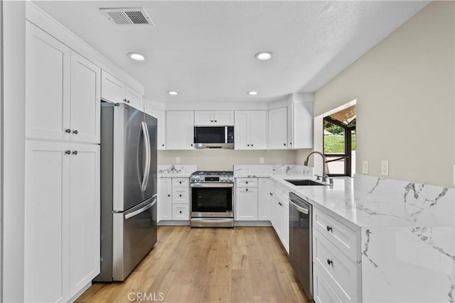 26337 Rainbow Glen Dr Unit 244, Newhall, CA 91321 - kitchen with appliances with stainless steel finishes, white cabinetry, light wood finished floors, light stone counters, and recessed lighting
