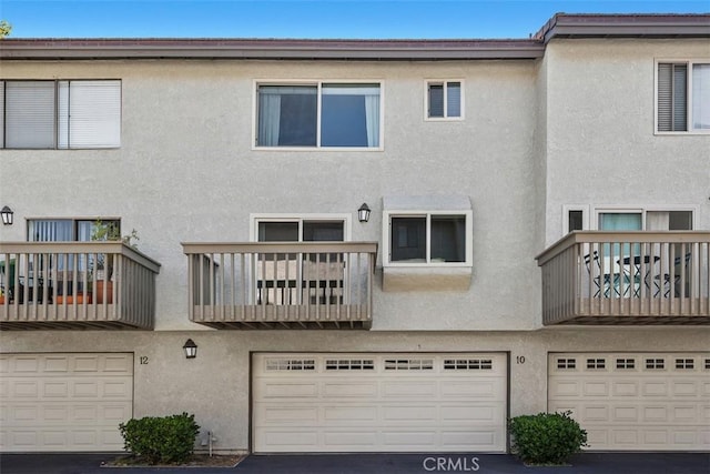 10 Starfall Unit 11, Irvine, CA 92603 - rear view of house featuring stucco siding, a garage, and a balcony