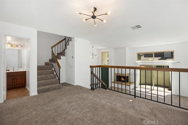 10 Starfall Unit 11, Irvine, CA 92603 - unfurnished living room featuring a chandelier, carpet floors, a lit fireplace, and stairway