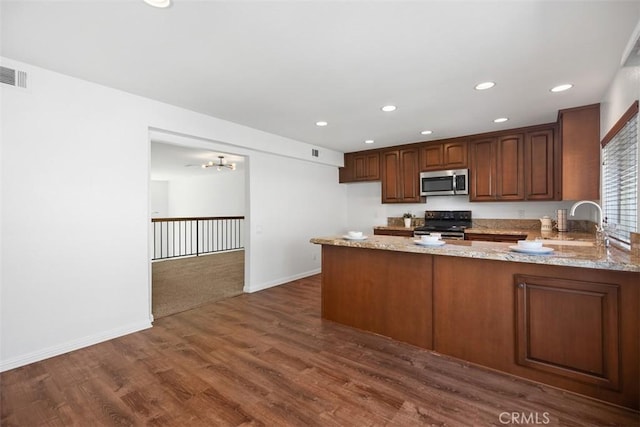 10 Starfall Unit 11, Irvine, CA 92603 - kitchen with stainless steel microwave, black range with electric cooktop, light stone countertops, a peninsula, and recessed lighting