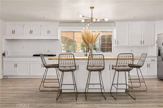 35356 Sierra Vista Dr, Agua Dulce, CA 91390 - kitchen featuring tasteful backsplash, a chandelier, stainless steel refrigerator with ice dispenser, a kitchen bar, and white cabinetry