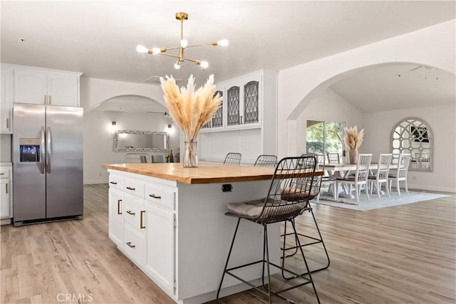 35356 Sierra Vista Dr, Agua Dulce, CA 91390 - kitchen with stainless steel refrigerator with ice dispenser, wooden counters, arched walkways, light wood-type flooring, and white cabinets