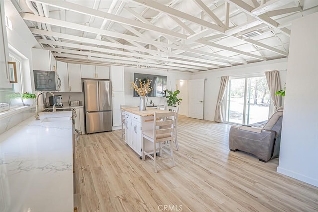 35356 Sierra Vista Dr, Agua Dulce, CA 91390 - kitchen featuring freestanding refrigerator, lofted ceiling, white cabinetry, light wood-style floors, and light stone counters