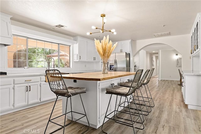 35356 Sierra Vista Dr, Agua Dulce, CA 91390 - kitchen with wood counters, arched walkways, stainless steel fridge, and light wood finished floors