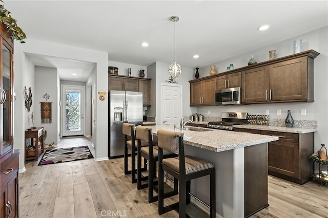 1616 Rosemary, Beaumont, CA 92223 - kitchen with stainless steel appliances, dark brown cabinets, light wood-type flooring, a kitchen bar, and recessed lighting