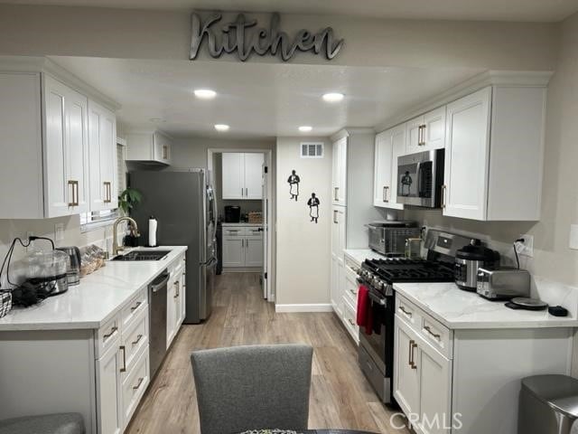 9827 Estacia Ct, Rancho Cucamonga, CA 91730 - kitchen featuring appliances with stainless steel finishes, light wood-style floors, white cabinetry, recessed lighting, and light stone counters
