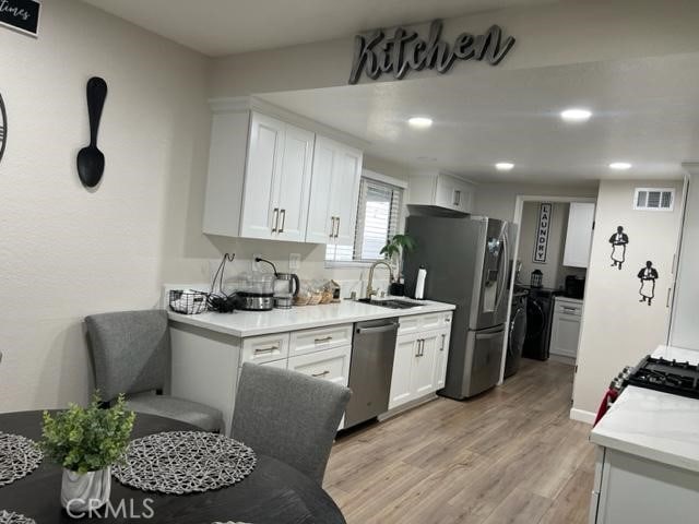 9827 Estacia Ct, Rancho Cucamonga, CA 91730 - kitchen with appliances with stainless steel finishes, white cabinets, light wood-style flooring, and recessed lighting