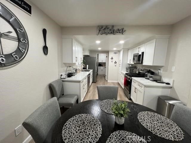 9827 Estacia Ct, Rancho Cucamonga, CA 91730 - kitchen with appliances with stainless steel finishes, light wood-style floors, white cabinets, light countertops, and recessed lighting