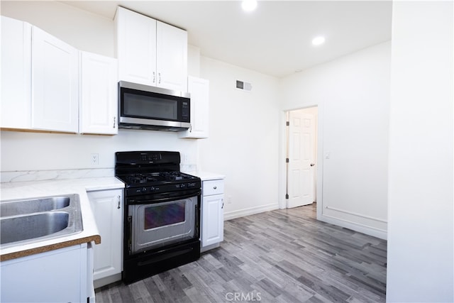 425 W 17th St, San Bernardino, CA 92405 - kitchen featuring stainless steel microwave, gas stove, wood finished floors, white cabinets, and recessed lighting