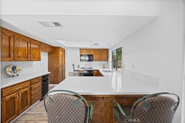 601 Las Arenas Ct, Bakersfield, CA 93314 - kitchen with black microwave, light countertops, a peninsula, light wood-style floors, and backsplash