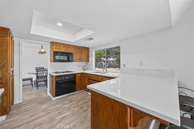 601 Las Arenas Ct, Bakersfield, CA 93314 - kitchen featuring black appliances, a peninsula, light countertops, a tray ceiling, and light wood-type flooring