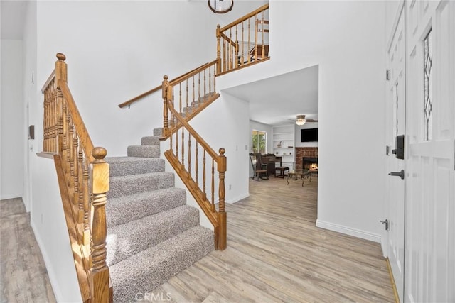 601 Las Arenas Ct, Bakersfield, CA 93314 - entryway with wood finished floors, stairway, ceiling fan, a towering ceiling, and a warm lit fireplace