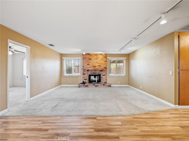 17911 Juniper St, Hesperia, CA 92345 - unfurnished living room featuring track lighting, light wood-type flooring, a fireplace, ceiling fan, and light colored carpet