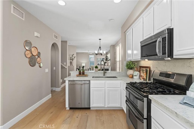 14 Tall Oak, Irvine, CA 92603 - kitchen featuring appliances with stainless steel finishes, arched walkways, a peninsula, white cabinets, and recessed lighting
