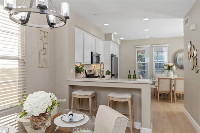 14 Tall Oak, Irvine, CA 92603 - kitchen with appliances with stainless steel finishes, a chandelier, light wood-type flooring, light countertops, and white cabinets