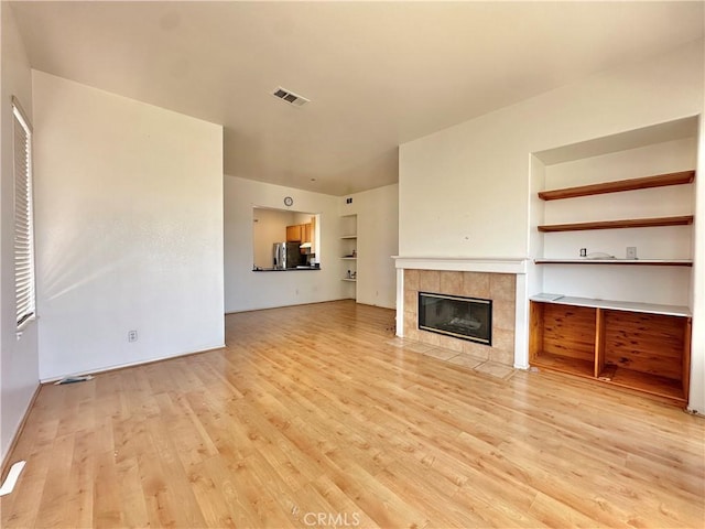 2244 Posada Ct, Corona, CA 92879 - unfurnished living room with light wood-style floors, a tiled fireplace, and built in shelves