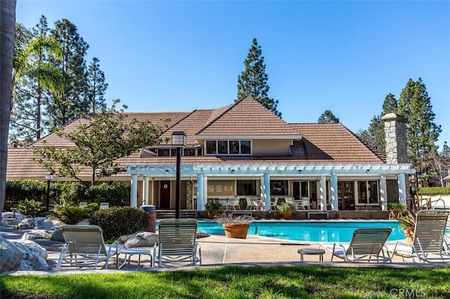 2567 Plaza Del Amo Unit 205, Torrance, CA 90503 - back of property featuring an outdoor pool, a patio area, a tile roof, a pergola, and a chimney