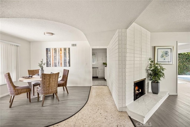 557 S Gardner Dr, Orange, CA 92866 - dining space with a textured ceiling, a brick fireplace, and speckle patterned floor