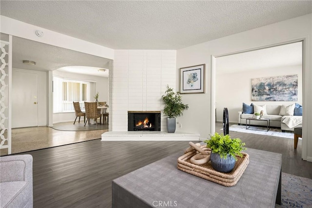 557 S Gardner Dr, Orange, CA 92866 - living room featuring arched walkways, a textured ceiling, wood finished floors, and a fireplace