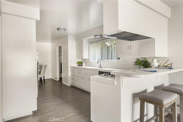 557 S Gardner Dr, Orange, CA 92866 - kitchen featuring a breakfast bar area, a peninsula, white cabinets, dark wood-style floors, and light countertops
