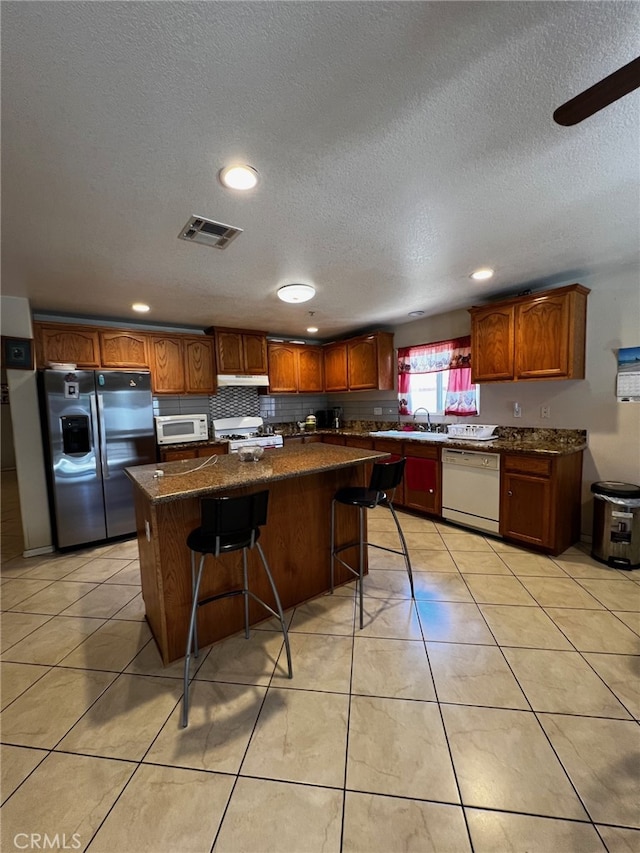 2932 Prospect Ave, Riverside, CA 92507 - kitchen with white appliances, a center island, under cabinet range hood, recessed lighting, and a textured ceiling