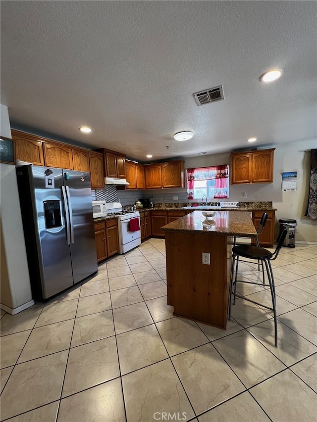 2932 Prospect Ave, Riverside, CA 92507 - kitchen with white appliances, a kitchen island, a textured ceiling, recessed lighting, and a kitchen breakfast bar
