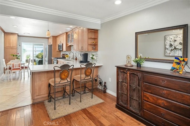 18912 Circle Of The Oaks, Newhall, CA 91321 - kitchen featuring appliances with stainless steel finishes, a breakfast bar, ornamental molding, decorative backsplash, and a peninsula