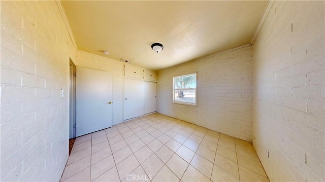 21845 Fox Ave, Apple Valley, CA 92307 - unfurnished bedroom featuring ornamental molding, light tile patterned floors, a closet, and brick wall