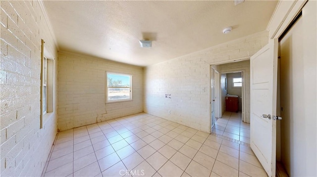 21845 Fox Ave, Apple Valley, CA 92307 - empty room with brick wall, plenty of natural light, a smoke detector, and light tile patterned floors