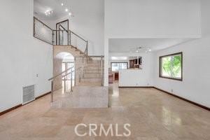 25152 Mammoth Cir, Lake Forest, CA 92630 - unfurnished living room featuring stairway, a towering ceiling, arched walkways, and concrete floors