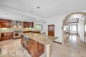 25152 Mammoth Cir, Lake Forest, CA 92630 - kitchen featuring arched walkways, plenty of natural light, a center island, brown cabinets, and recessed lighting